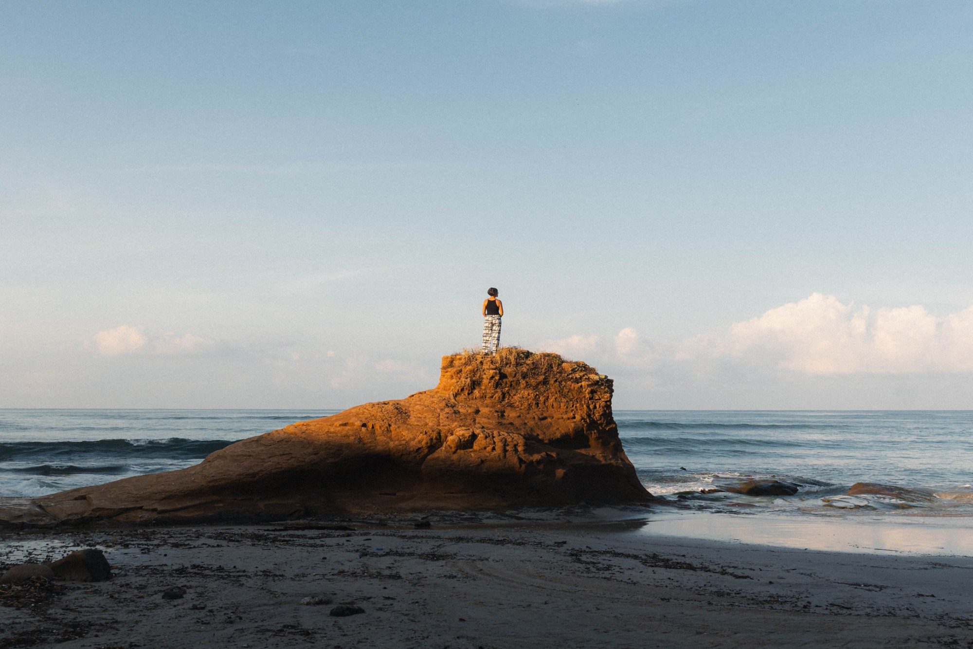 A guest standing on a rock at sunrise, looking out over the sea